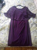 Front view of purple chiffon overlay dress on hanger