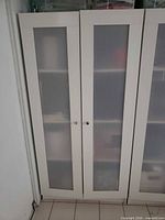Front view of closed cabinet showing double frosted doors