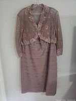 Full view of mauve dress and matching lace bolero on hanger
