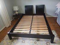 Full view of queen platform bed frame with slats, twin panel headboard, and attached side table