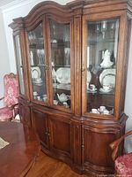 Front angled view showing entire china cabinet with glass doors, interior shelves, and lower storage