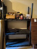 Front view of black plastic 3-shelf unit with items on shelves (contents not included)