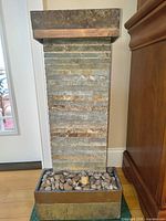 Front view of slate stacked stone tabletop fountain with copper top and base