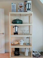 Shelf view showing boxed OGGI carafe, CircleGlass dispenser, West Bend urn, green roasting pan, glass cups, ceramic pieces, coffee maker and pitcher