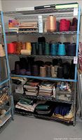 Full front view of 5-tier blue metal wire shelving loaded with yarn and books