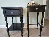 Front view of both black side tables showing drawers with glass knobs and turned legs