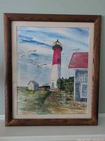 Frontal view of framed watercolor painting showing lighthouse scene