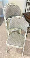 Stack of four SuddenComfort folding chairs showing front chair with patterned upholstery