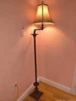Full view of lamp lit showing height, base, shade, swing arm