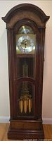 Full frontal view of the Seth Thomas grandfather clock showing face, pendulum and weights