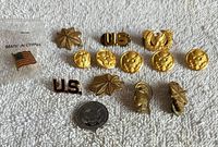 All ten pins laid out on white towel including bagged flag pin for scale reference