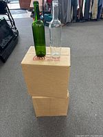 Two sample bottles (green, clear) on top of two closed cartons