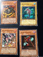All four Yu-Gi-Oh! cards in sleeves on black background