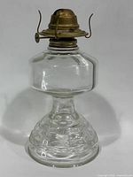 Full view of clear glass oil lamp with brass burner attached