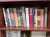 Shelf of assorted hardcover books showing various spine designs, colors and titles
