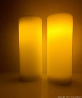 Front view of both ivory wax flameless candles illuminated