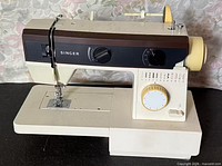 Front left view of Singer sewing machine showing brand label, needle area, base, control panel