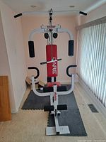 Front view of Care multi-station home gym showing frame, seat, press arms and leg attachment