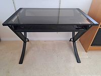 Front view showing full desk, metal frame, glass top, under-shelf