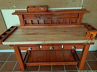 Full view of custom hardwood workbench with vise and back panel