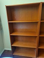 Front view of tall wooden bookcase showing four shelves and open back