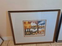 Framed print with autumn lake scene, ornate bronze frame, white mat