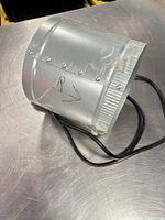 Side view of galvanized steel duct fan showing cylindrical housing and power cord