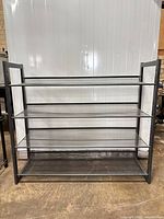 Front view of gray metal shelving unit showing four mesh shelves