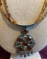 Close view of pendant showing cabochons and bead fringe
