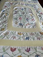 Full view of quilt on bed showing overall floral vine pattern and yellow sashing