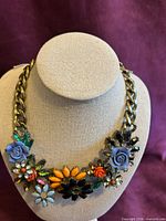 Full view of necklace on bust showing gold-tone curb chain and multicolored floral bib section
