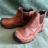 Side profile of both boots showing leather uppers, elastic gores, rubber toe caps, outsole tread