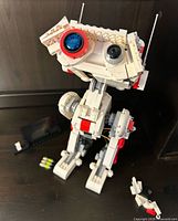 Front view of assembled LEGO BD-1 with loose accessory pieces