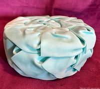 Side view of turquoise pillbox hat showing draped tulle folds
