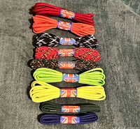 Nine pairs of laces stacked, paper wraps visible
