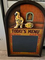 Front view of arched chalkboard sign with raised chef figure and "Today’s Menu" text