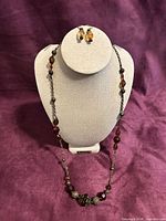 Full view of necklace on display bust with matching earrings shown above