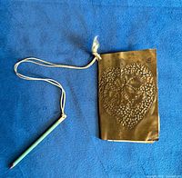 Front view of brass scorebook with attached pencil