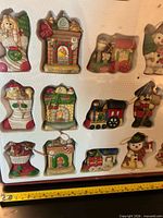 Tray showing lower left section of ornaments including Santa, fireplace, train, stocking, cottage, teddy bear