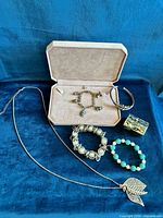 All six items displayed: trinket box, charm bracelet, silver cuff, faux pearl bracelet, turquoise bead bracelet, leaf necklace