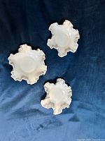 Three white Fenton hobnail milk glass dishes displayed on dark surface