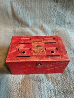 Closed red metal Budget Bank coin sorter showing lithographed label and paint wear