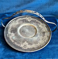 Top view of round silver-plated tray showing engraved border and pierced handle