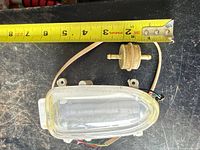 Top view of light fixture next to measuring tape and fuel filter