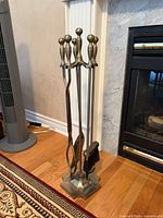 Full view of brass fireplace tool set on stand