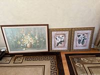 group shot of three framed floral artworks leaning against wall