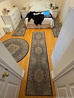 Bedroom view showing three runners and partial round rug on wooden floor