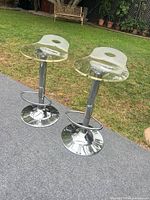 Two clear acrylic bar stools on lawn showing full form and condition
