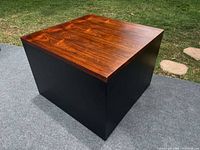 Three-quarter view of cube table showing walnut veneer top and black sides