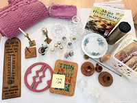 All items laid out including cookbook, thermometer, dishware, candleholders, glassware, trivets, linens